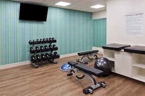 A fitness center with exercise equipment, a wall-mounted TV, and a sign listing rules and regulations. - Holiday Inn Express & Suites Fayetteville by IHG (Fayetteville)