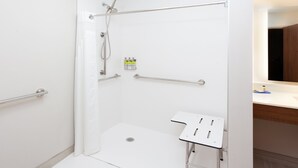 A modern bathroom with a glass-enclosed shower, a white sink with a mirror, and a wooden vanity. - Holiday Inn Express & Suites Fayetteville by IHG (Fayetteville)