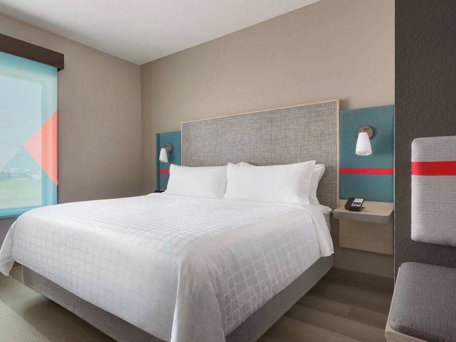 Quarto de hotel com cama grande, mesas de cabeceira, janela com vista e telefone fixado na parede.