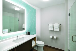 Ein modernes Badezimmer mit großem Spiegel, weißem Waschbecken und Toilette.