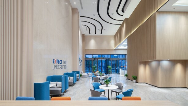 A modern lobby with a 'EXPECT THE UNEXPECTED' sign, seating areas, and a view of the city through large windows. - Holiday Inn Express Nanchang Qingshan Lake View by IHG (Nanchang)
