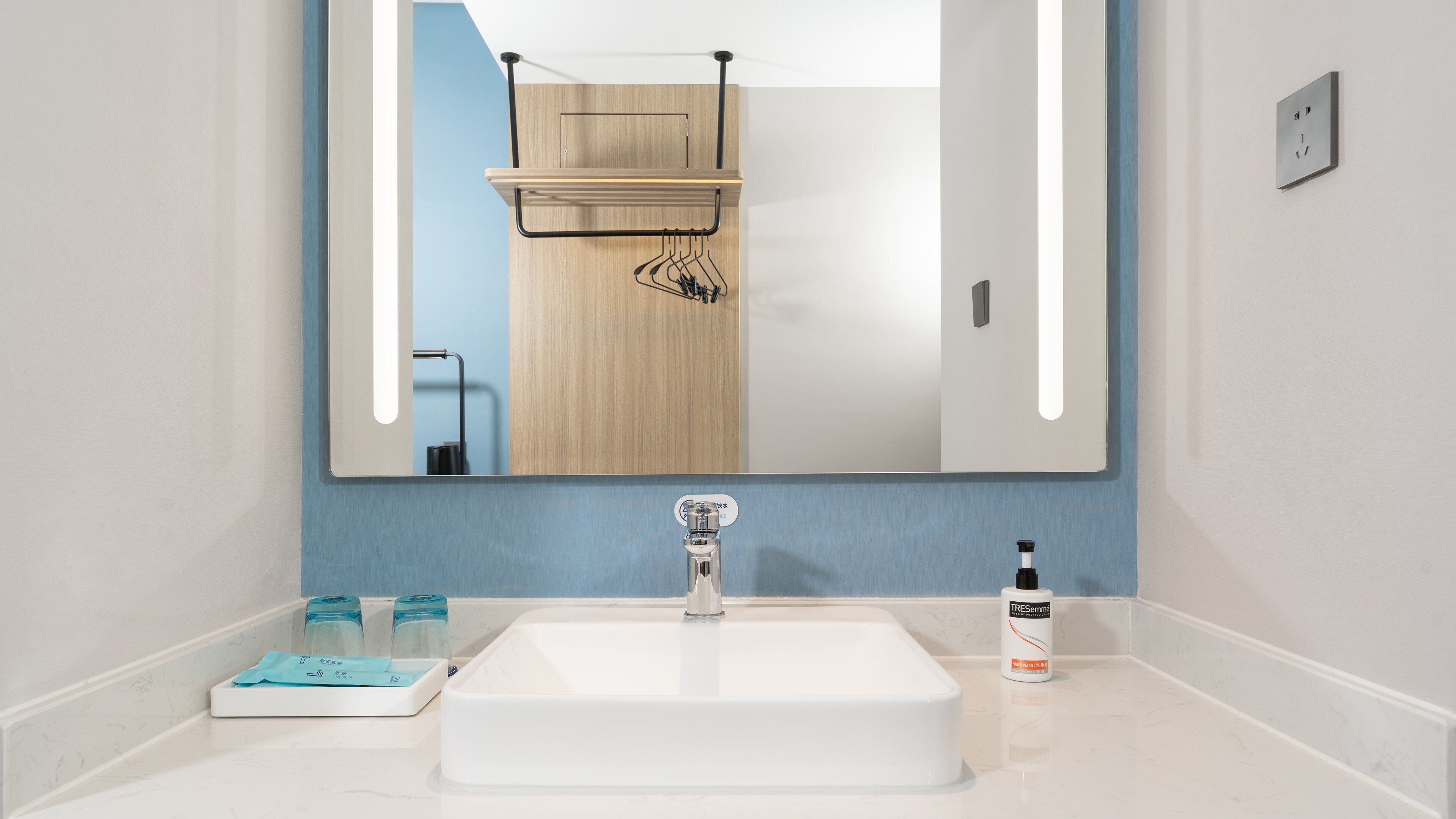 Un baño con un lavamanos blanco, un espejo y un dispensador de toallas.