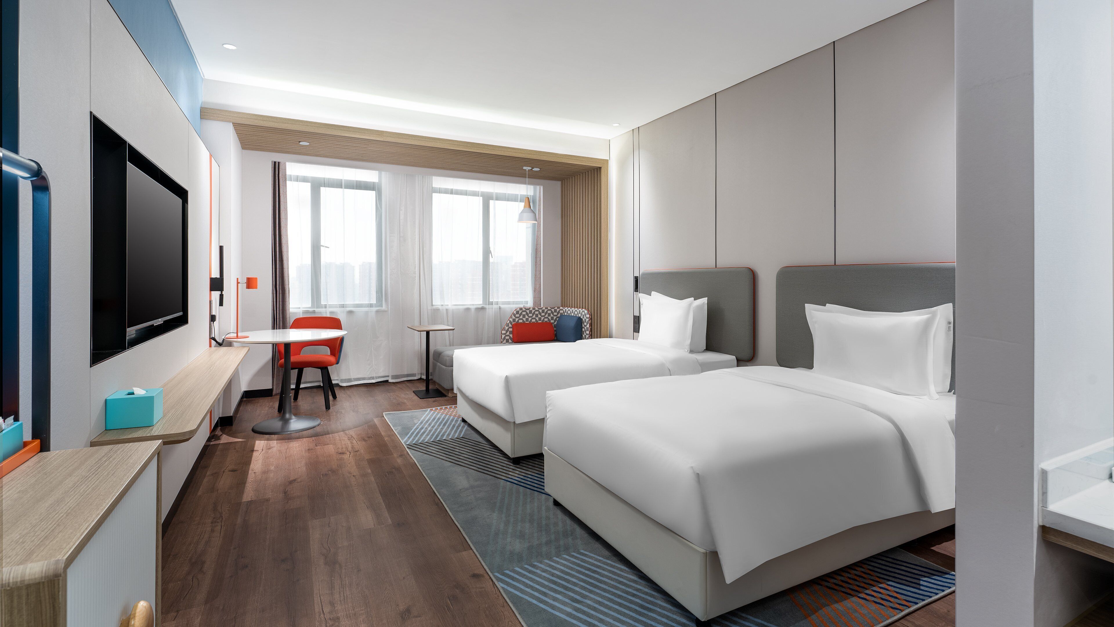 Una habitación de hotel con dos camas, televisión, escritorio y una silla.