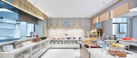 Una cocina moderna con electrodomésticos de acero inoxidable, encimeras blancas y lámparas colgantes.