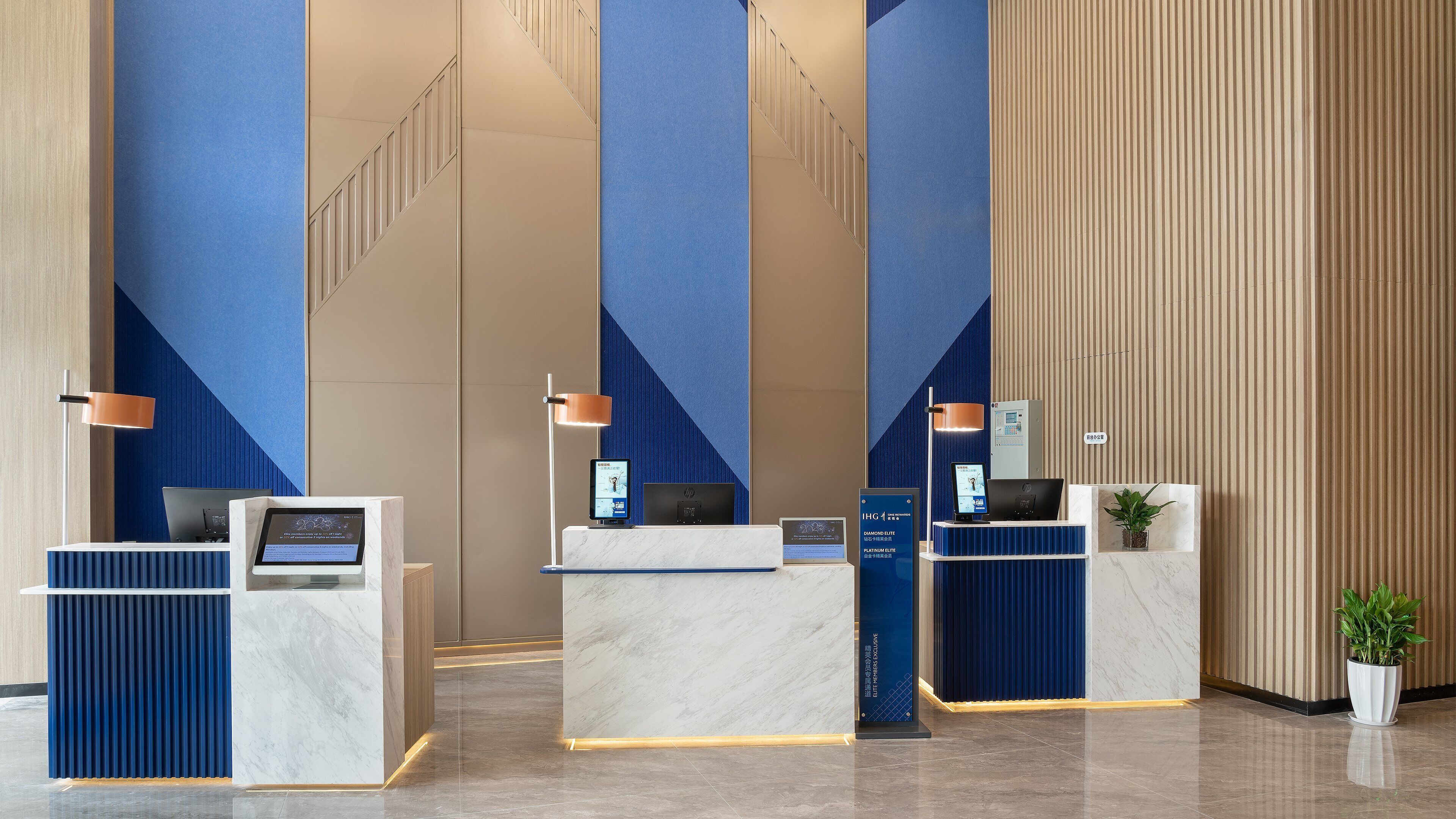 A modern reception area with marble counters, blue and beige walls, and a clean, minimalist design.