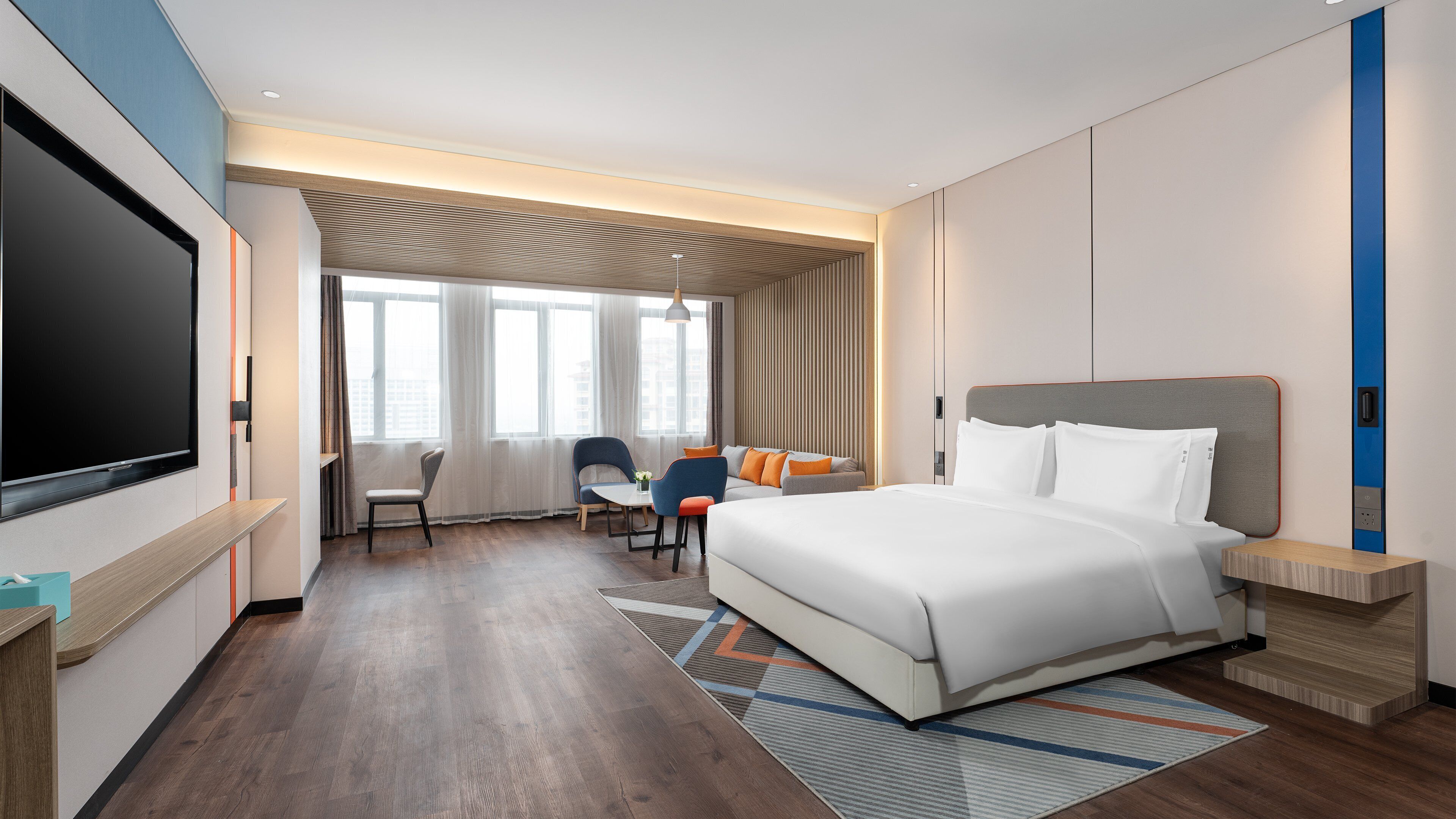 Una habitación de hotel moderna con una cama grande, televisión, escritorio y una silla.