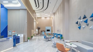 A modern hotel lobby with a reception desk, seating areas, and a large wall with geometric decorations. - Holiday Inn Express Nanchang Qingshan Lake View by IHG (Nanchang)