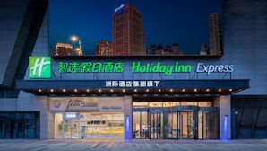 A Holiday Inn Express hotel with a prominent sign, a glass entrance, and a view of the city skyline in the background. - Holiday Inn Express Nanchang Qingshan Lake View by IHG (Nanchang)