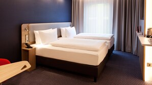A hotel room with a large bed, bedside tables, a desk, and a chair.