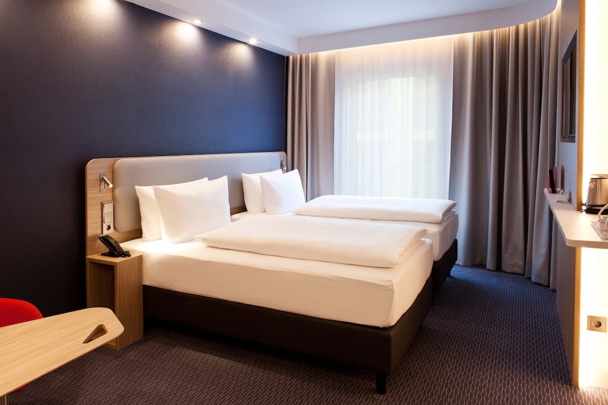 A hotel room with a large bed, bedside tables, a desk, and a chair.