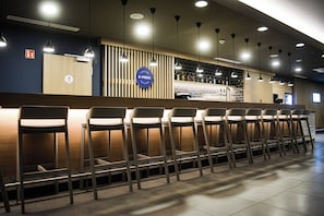 A bar area with a counter, multiple chairs, and overhead lighting. - Holiday Inn Express Munich Olching by IHG (Olching)