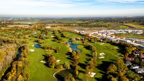 Vista aérea de un campo de golf con un club de campo, búnkeres de arena y un estanque.