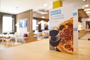 A menu board with a pizza image and text in a restaurant setting.