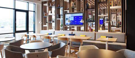 A modern library with bookshelves, seating areas, and a digital display.