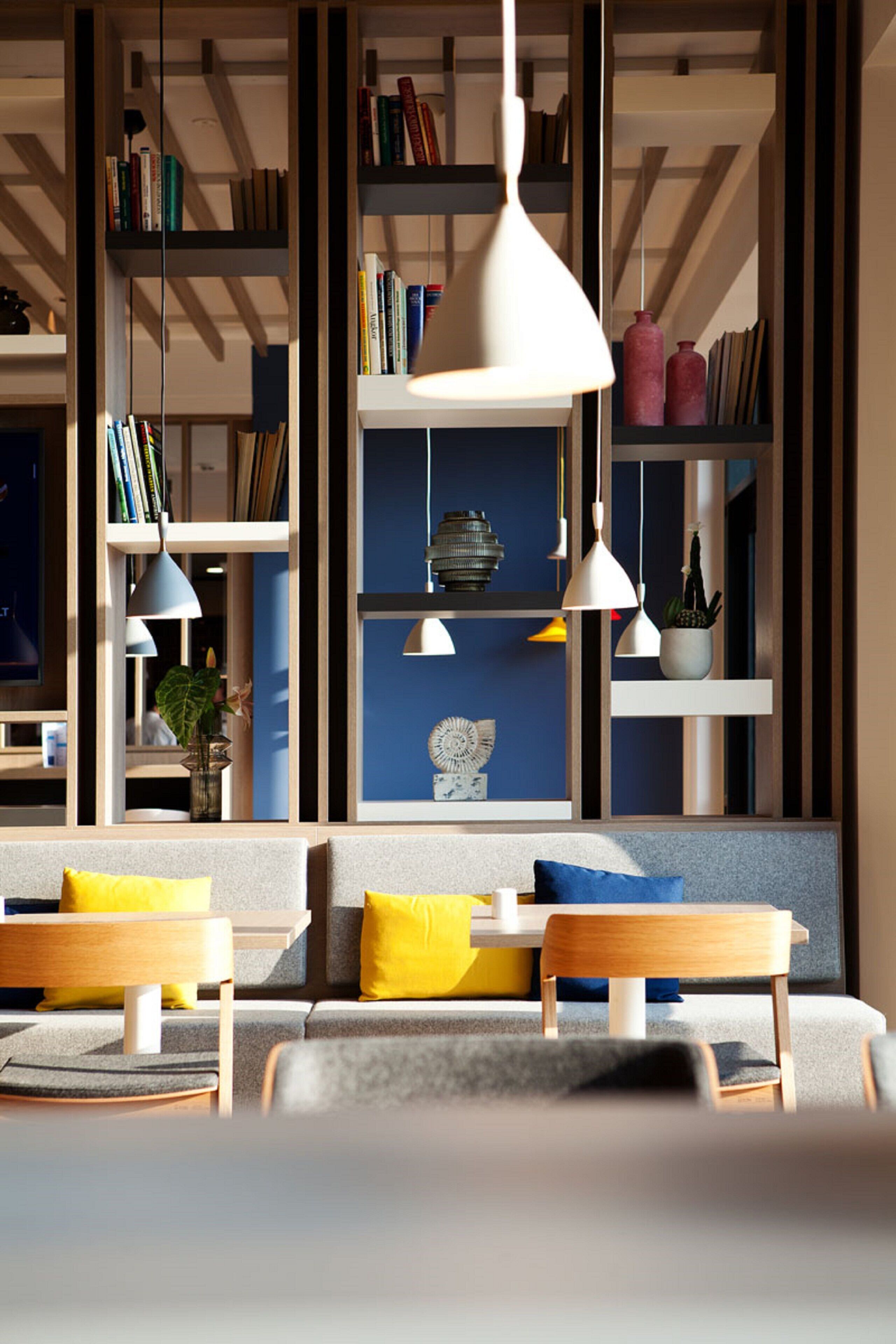 A modern living room with a sofa, two chairs, a coffee table, and a bookshelf filled with books.