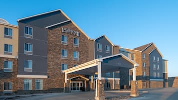 Un hotel Staybridge Suites con fachada de ladrillo, múltiples ventanas y una entrada cubierta.