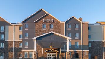 Un hotel Staybridge Suites con fachada de ladrillo, múltiples ventanas y una entrada cubierta.