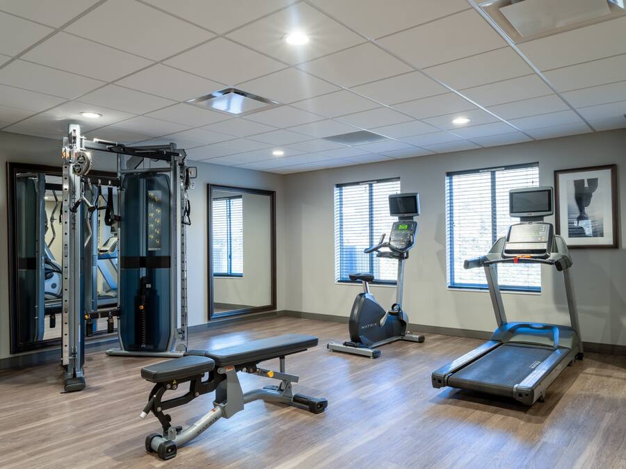 A gym with cardio machines, weight training equipment, and large windows.