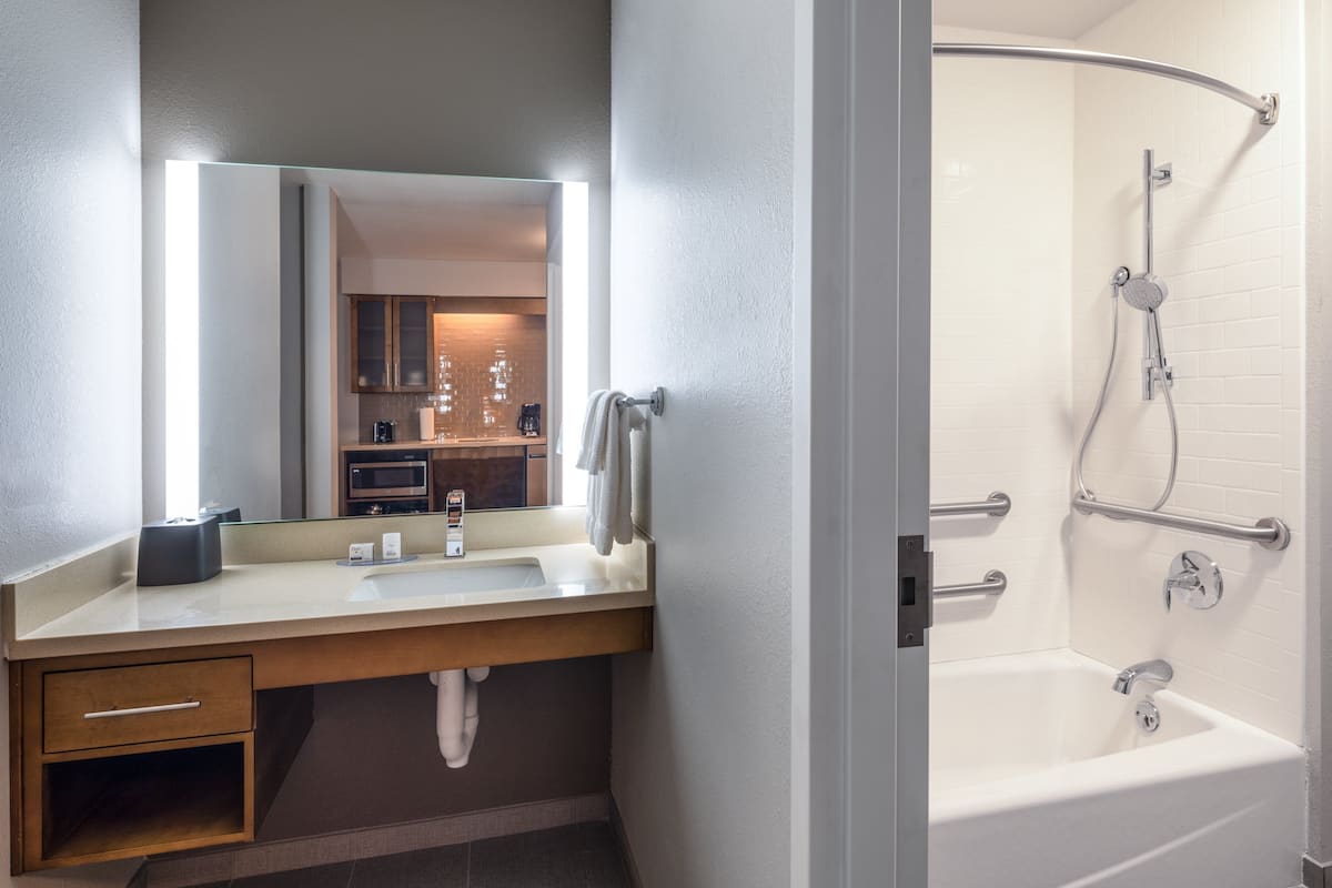 A modern bathroom with a sink, mirror, and shower.