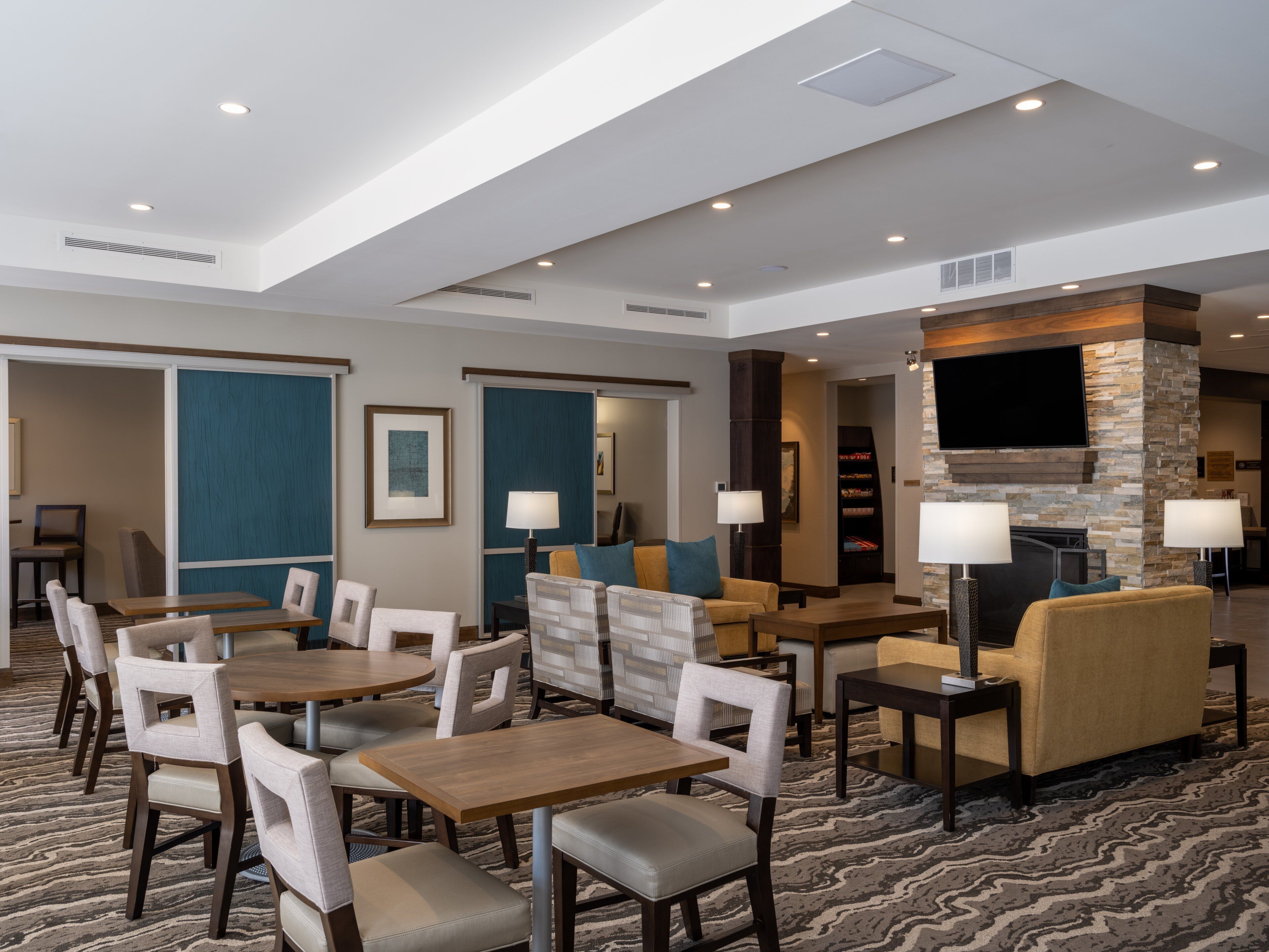 Een hotellobby met een ruime zithoek, een open haard en een flatscreen televisie die aan een stenen muur is bevestigd.