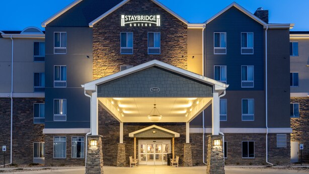 A Staybridge Suites hotel with a stone facade, multiple windows, and a covered entrance area. - Staybridge Suites Sioux City Southeast by IHG (Sioux City)