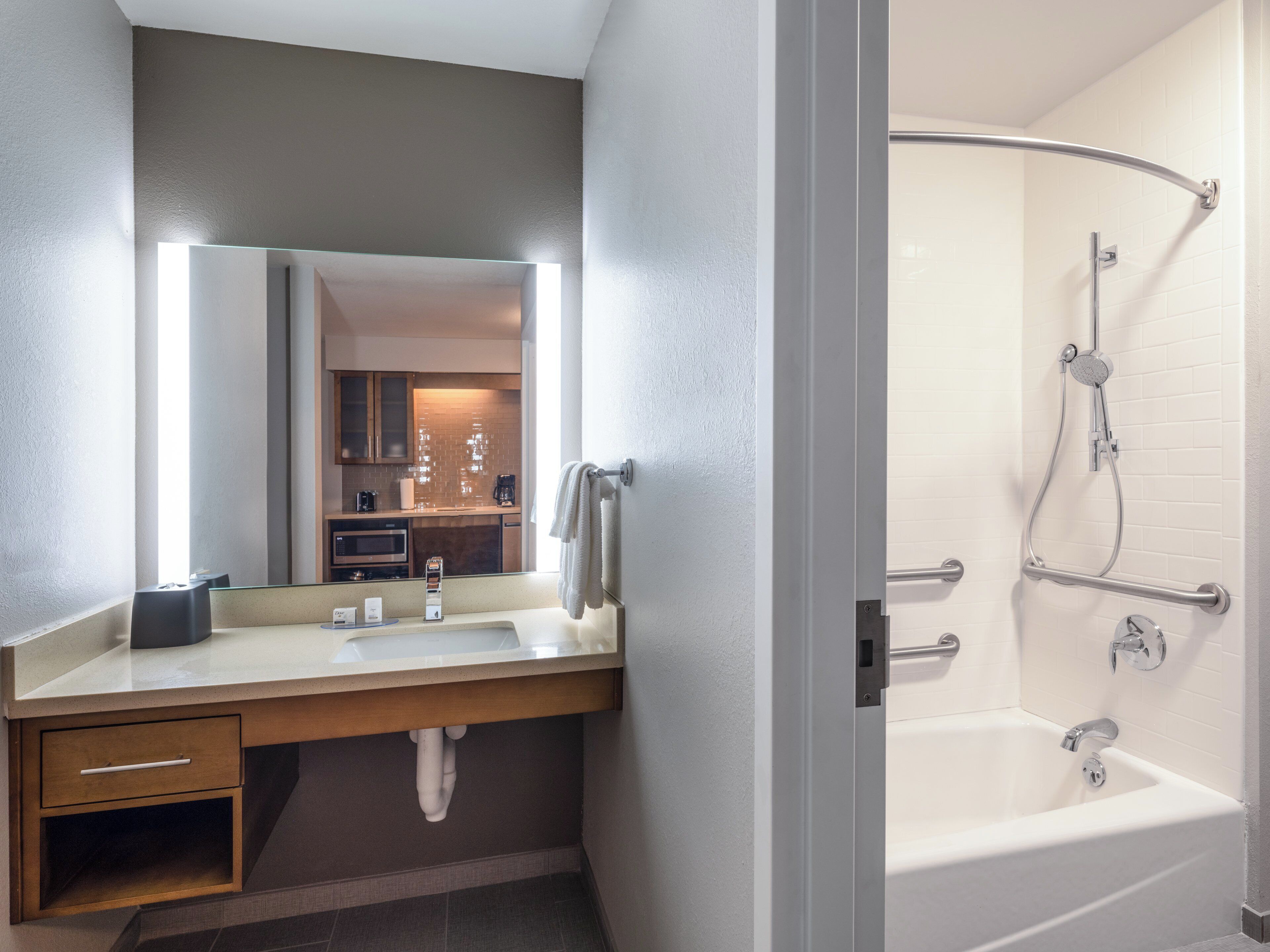 Un baño moderno con tocador, espejo, lavabo y ducha.