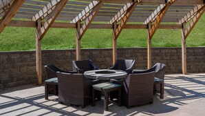 A covered patio area with wicker furniture and a stone wall. - Staybridge Suites Sioux City Southeast by IHG (Sioux City)