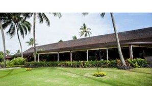 A hotel with a long, covered veranda, palm trees, and well-maintained lawns. - One Bedroom Garden View Kauai Coast Available 12/23-12/30/2025 (Kapaa)