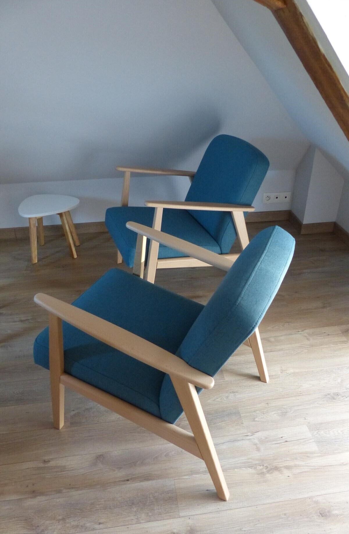 A room with two blue armchairs and a small white table.