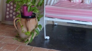 Un rincón acogedor con un banco de metal y cojines, una planta en maceta y una chimenea de piedra.