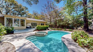 Une maison avec une piscine, un patio couvert et un jardin.