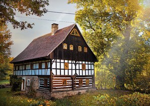 Ein traditionelles Fachwerkhäuschen mit steilem Dach, einem sichtbaren Schornstein und einer kleinen Veranda.