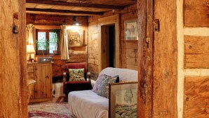 Un chalet rustique en bois doté d’une chambre confortable comprenant un lit simple, une chaise, un bureau avec une lampe et une fenêtre avec des rideaux.