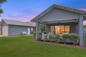 Una casa moderna con un portico coperto, un prato e un garage.