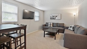 Ein Wohnzimmer mit einer Couch, einem Couchtisch und einem Fernseher.