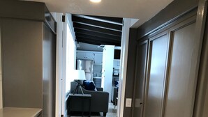 Un pasillo que conduce a una sala de estar con un sofá, una lámpara y una alfombra.