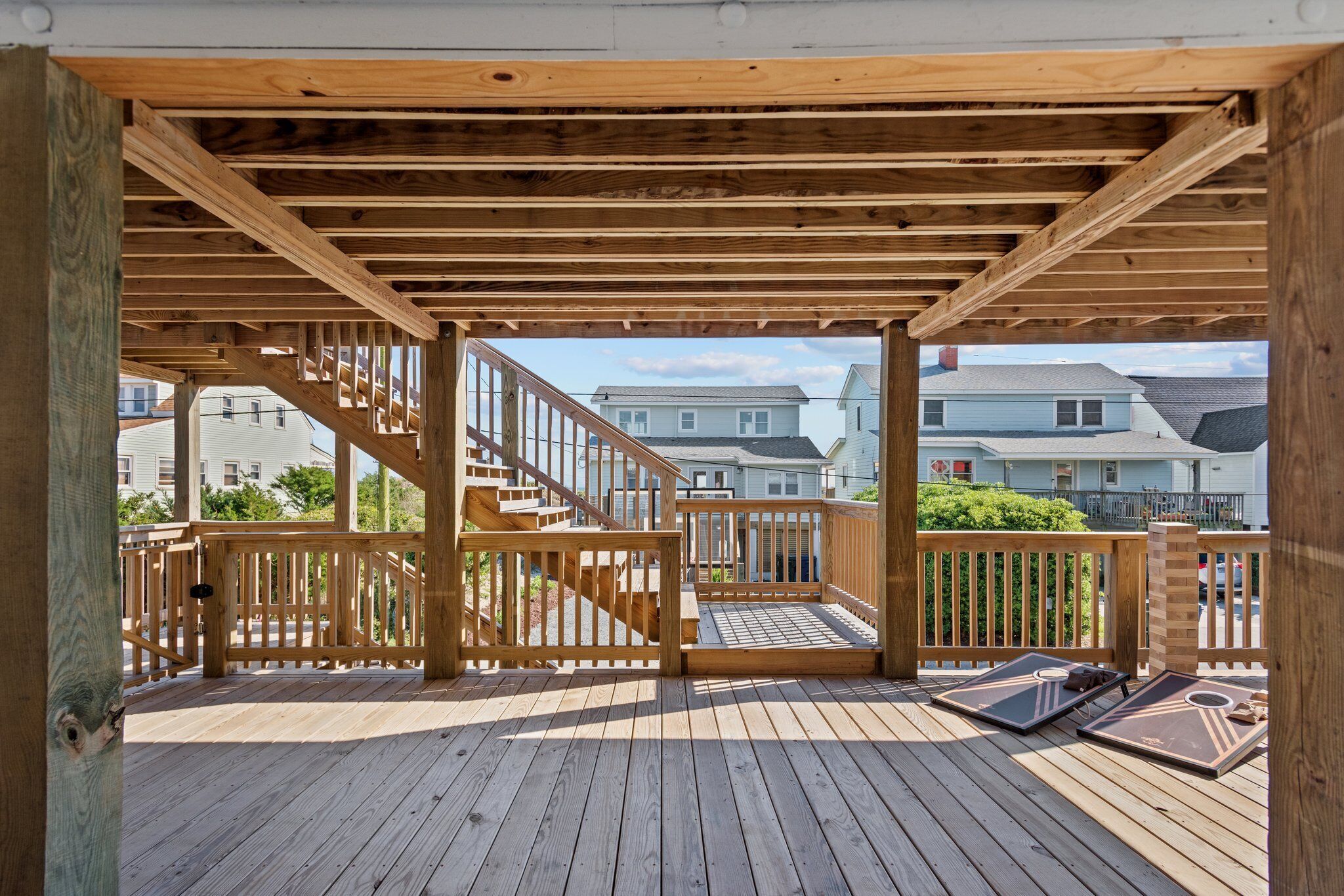 Une terrasse en bois avec un escalier menant à une zone abritée, d’où l’on a vue sur un quartier résidentiel.