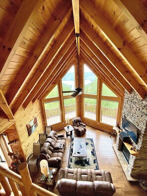 A spacious loft-style room with a high ceiling, large windows, a fireplace, and a cozy seating area. - MOUNTAIN TOP CABIN WITH PARTNERING MARINA ON NORRIS LAKE (New Tazewell)