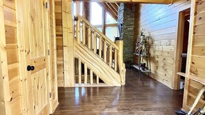 Interior de madera con una escalera, paredes de madera y una lámpara colgante.