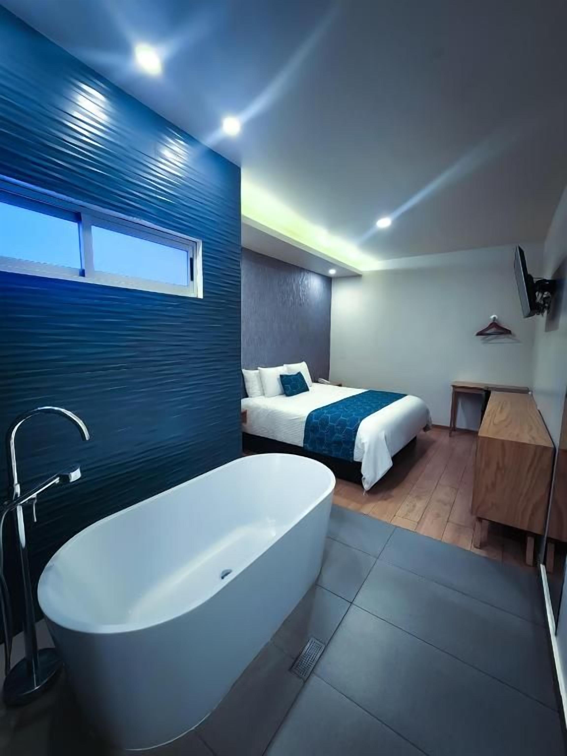 Un baño moderno con una bañera independiente, zona de ducha y una mesita de noche.