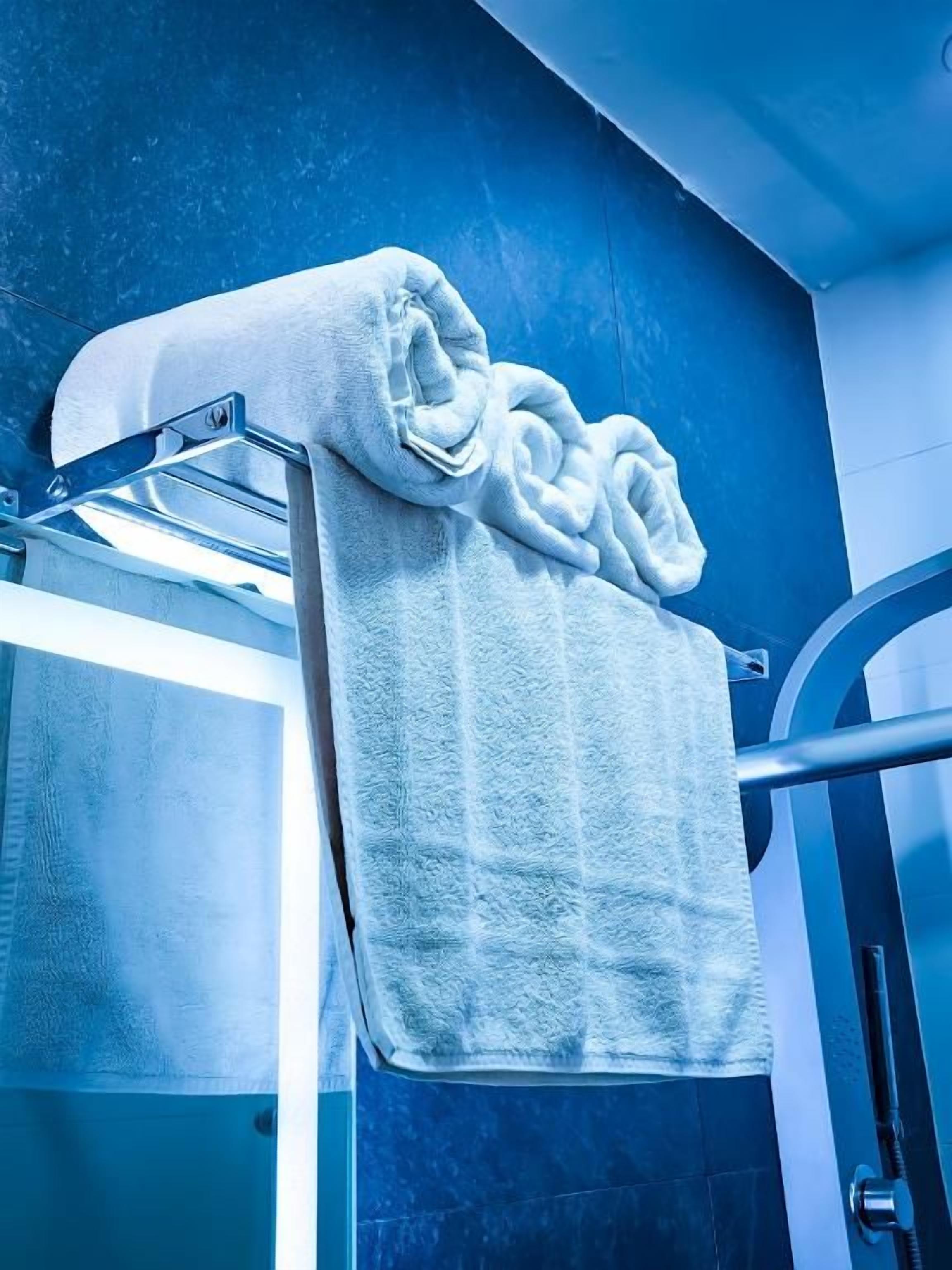 A bathroom with a towel rack holding a rolled towel.