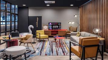A modern living room with a large flat-screen TV, comfortable seating, and a colorful rug.