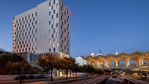 A modern hotel with a grid-like facade and a distinctive pink neon sign. - Moxy Lisboa Oriente (Lisbon)