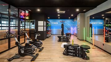 A modern gym with cardio equipment, weightlifting stations, and motivational wall graphics.