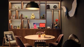 Una sala de estar moderna con una mesa redonda de madera, cuatro sillas, una estantería con diversos objetos decorativos y un aplique de pared.