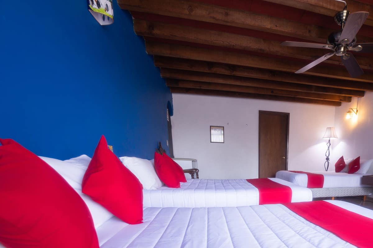 Een slaapkamer met een bed, een plafondventilator en een nachtkastje.