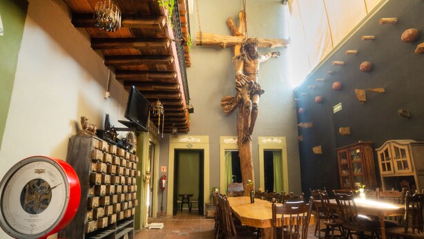Un comedor con una cruz de madera, un reloj y una pared con estanterías de madera.