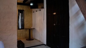 Una habitación pequeña y poco iluminada, con una pared de azulejos, una puerta de madera y una mesita con un espejo.