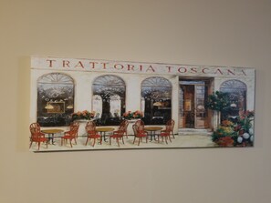 A painting of a restaurant named 'Trattoria Toscana' with outdoor seating and arched windows.