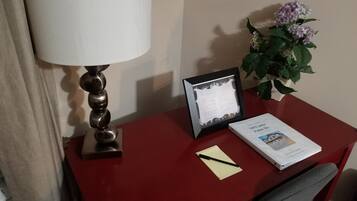 Een bureau met een lamp, een lijst met een document, een notitieboek, een boek en een kamerplant.